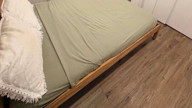 A single-bed room with a wooden frame, a green mattress, and a white throw blanket. - Room to Stay in Niagara Falls (Niagara Falls)