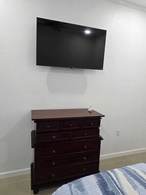 A bedroom with a bed, a dresser, and a mounted television. - Hillside Escape with Stunning Ocean Horizon Views (St Thomas)