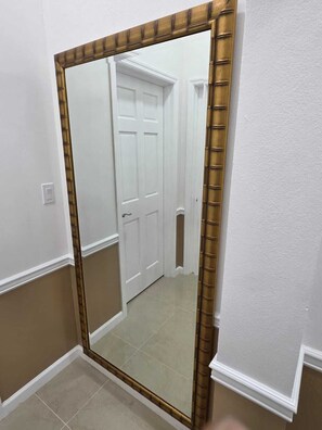 A hallway with a large mirror, white walls, and a door. - Hillside Escape with Stunning Ocean Horizon Views (St Thomas)