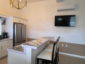 Eine moderne Küche mit integrierter Kochinsel, Edelstahlgeräten und einem an der Wand befestigten Flachbildfernseher.