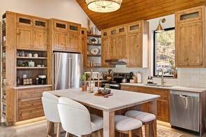 Une cuisine moderne avec des meubles en bois, un réfrigérateur en acier inoxydable et un îlot central doté de sièges.