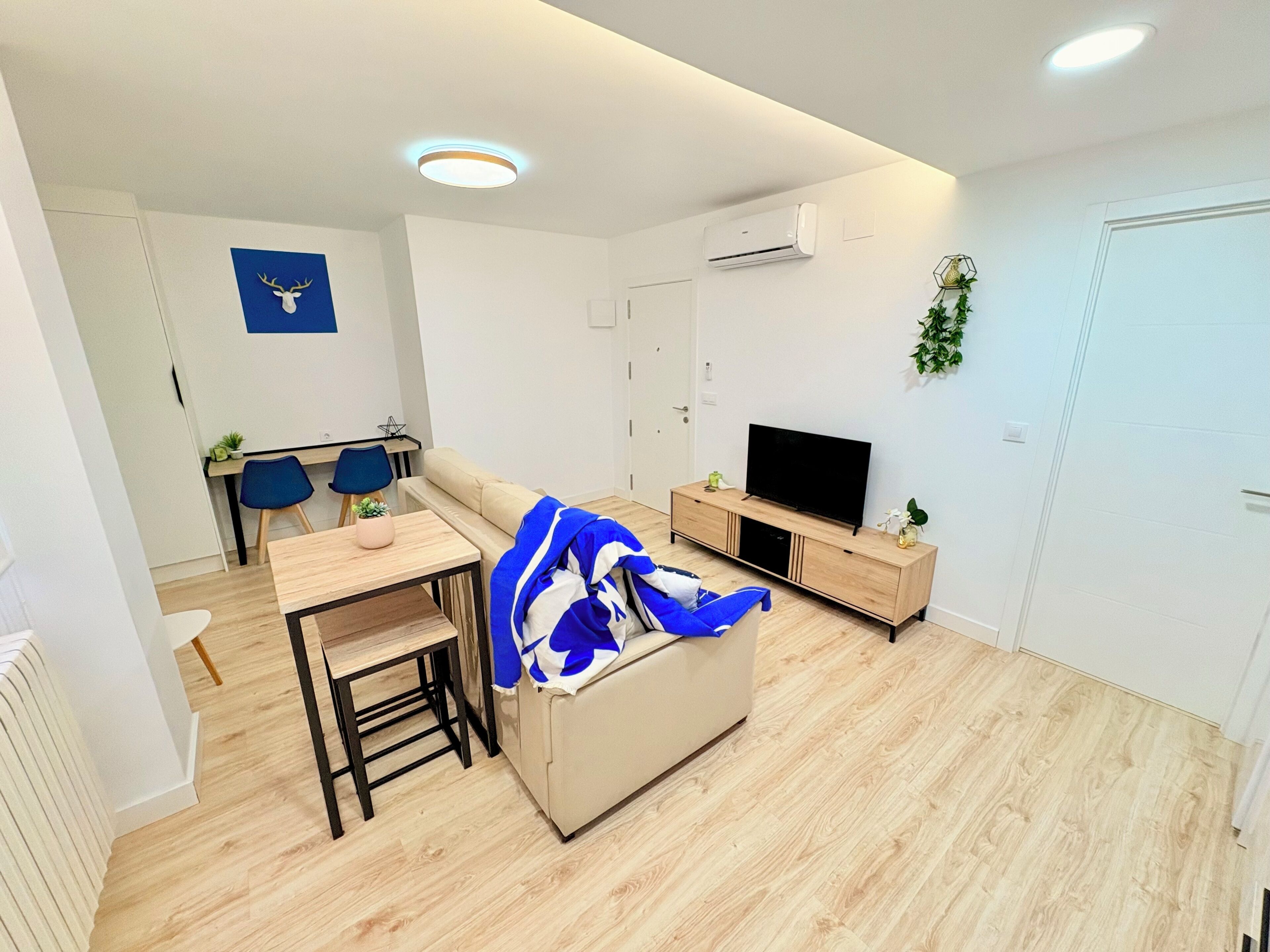 Una sala moderna con sofá, televisor y un comedor con sillas y una mesa.