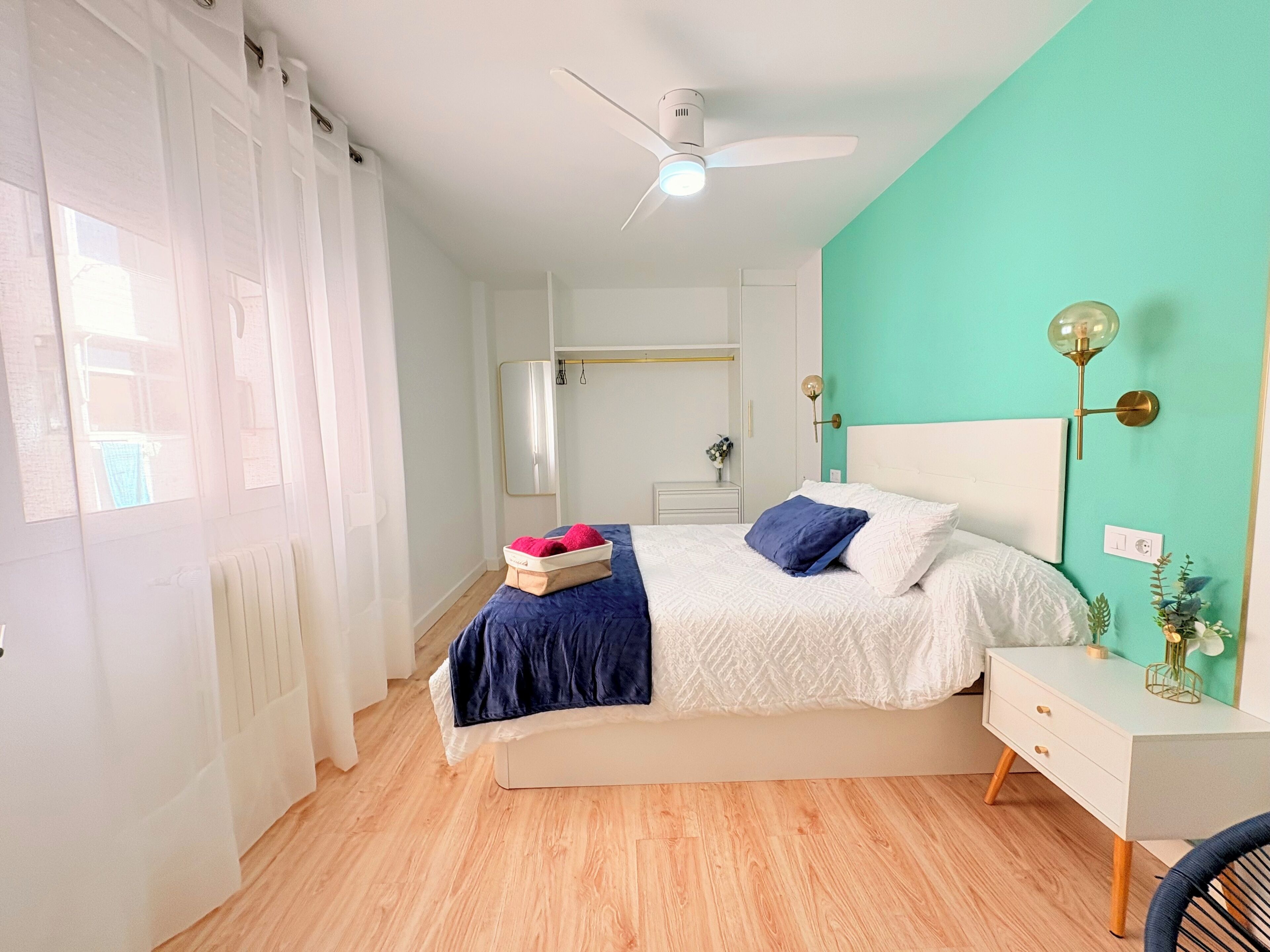 Un dormitorio con cama, mesita de noche y ventilador de techo.