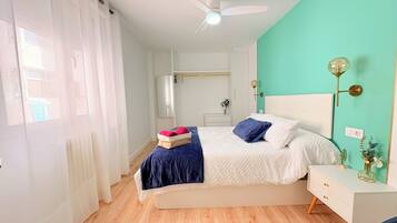 Un dormitorio con cama, mesita de noche y ventilador de techo.