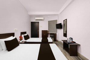A hotel room with two beds, a desk, a chair, a TV, and an air conditioning unit.