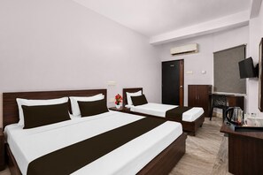 A hotel room with two beds, a wardrobe, a television, and a coffee maker.