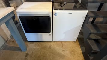 A compact, white appliance with a digital display, situated in a utilitarian space with concrete flooring and a brick wall.