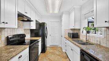 A kitchen with white cabinets, a black refrigerator, a microwave, and a dishwasher.