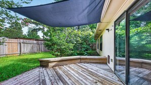 A wooden deck with a built-in bench, a large window, and a wooden fence in the background.