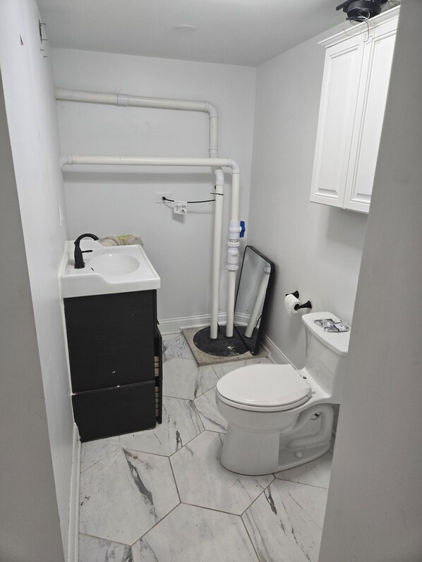 Une petite salle de bain avec des toilettes, un lavabo et un miroir.