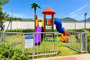 Un parque infantil con un tobogán, estructuras para escalar y una zona vallada.