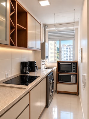 A modern kitchen with a built-in oven, a coffee maker, and a washing machine.