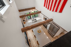 A modern kitchen with a central island, wooden beams, and a view of the outdoors. - Coastal Retreat in the Heart of Rockport: Walk to Beaches & Bearskin Neck (Rockport)