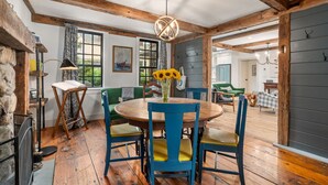Un'area pranzo rustica con un tavolo rotondo in legno, sedie blu e un vaso di girasoli.