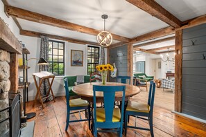 A rustic dining area with a round wooden table, blue chairs, and a vase of sunflowers. - Coastal Retreat in the Heart of Rockport: Walk to Beaches & Bearskin Neck (Rockport)