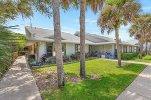 A residential building with a covered porch, a lawn, and a bicycle parked outside. - 🌊 Beachy Dreams | Non-Drive Beach NSB | Arcade + Paddleboard + Gear (New Smyrna Beach)