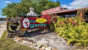 Segno di un ristorante con la scritta 'The Garlic' e l'elenco 'Pasta, Bistecche, Pesce'.