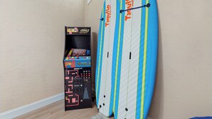 Una stanza con due tavole da surf appoggiate al muro e una console per videogiochi.