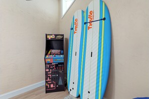 Ein Zimmer mit zwei Surfbrettern, die an der Wand lehnen, und einer Spielkonsole.