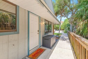 A residential property with a covered porch, a wooden fence, and a pathway leading to the entrance. - 🌊 Beachy Dreams | Non-Drive Beach NSB | Arcade + Paddleboard + Gear (New Smyrna Beach)