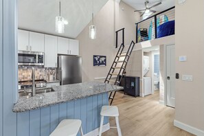 A modern kitchen with granite countertops, stainless steel appliances, and a bar area with stools.