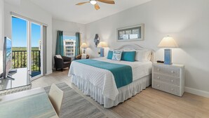 Un dormitorio con cama, dos lámparas de noche, ventilador de techo, vista al exterior y balcón.