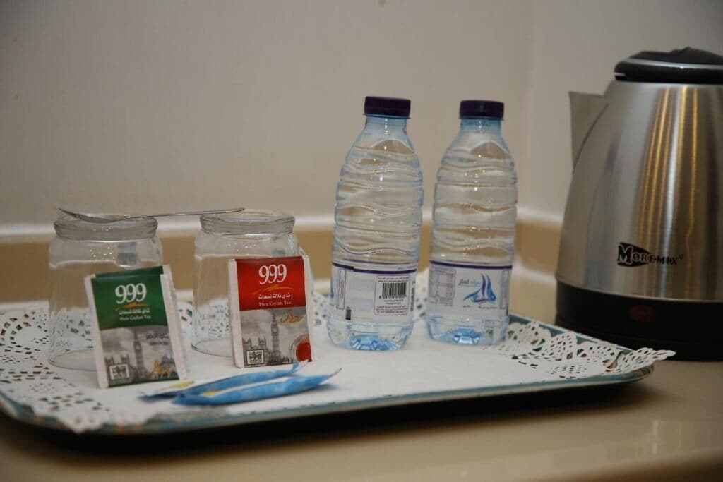A tray with two water bottles, a teapot, and two jars of tea on a table.