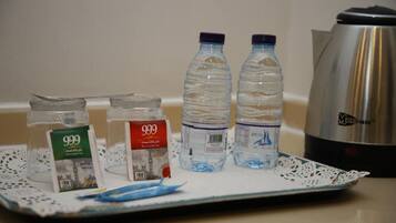 A tray with two water bottles, a teapot, and two jars of tea on a table.