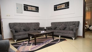 A living room with two grey sofas, a dark wooden coffee table, and a patterned rug.
