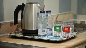 A stainless steel kettle, two water bottles, and two spice jars on a tray.