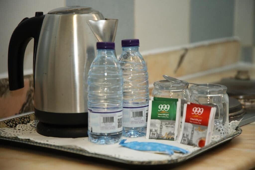 A tray with a kettle, water bottles, and two containers labeled '999'.