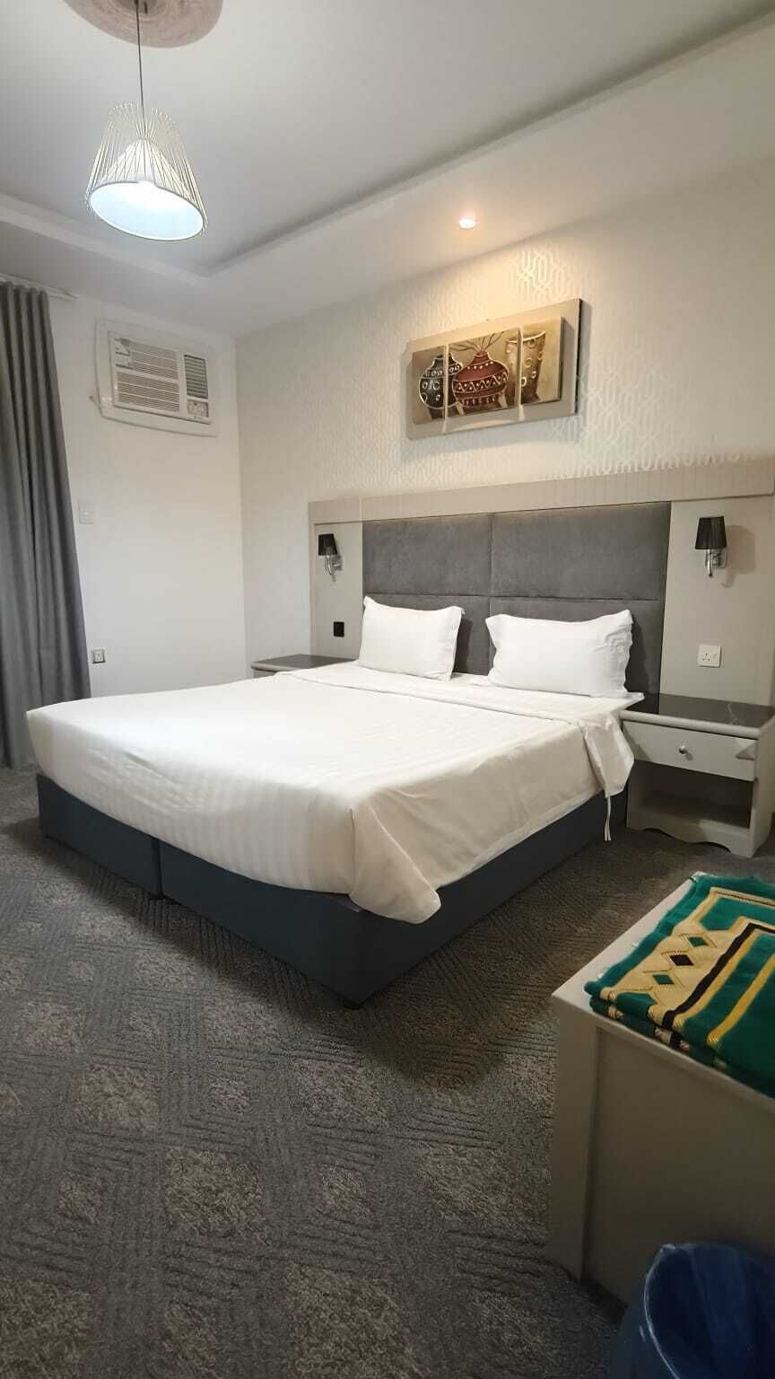 Ein Hotelzimmer mit einem großen Bett, Nachttischen, einer Lampe und einem dekorativen Wandbild.