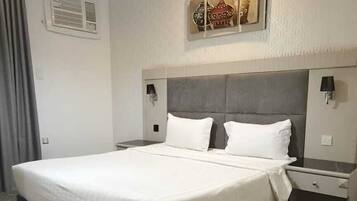 Ein Hotelzimmer mit einem großen Bett, Nachttischen, einer Lampe und einem dekorativen Wandbild.