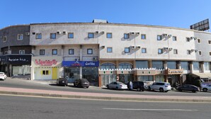 A multi-story building with several ground-level commercial spaces, including a clothing store and a café.