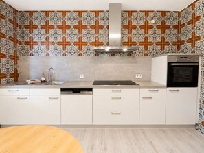 A modern kitchen with white cabinets, a stainless steel sink, and a built-in oven. - Greengarden Apartment for Construction Workers (Vilsheim)