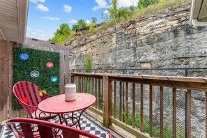 Ein Balkon mit Schachbrettboden, einem Metalltisch und zwei roten Stühlen.