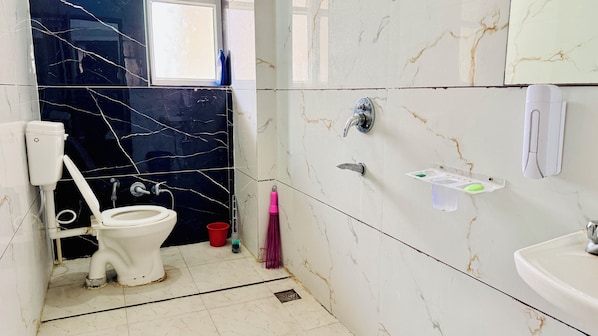 Une salle de bain comprenant des toilettes, un lavabo et un espace douche.