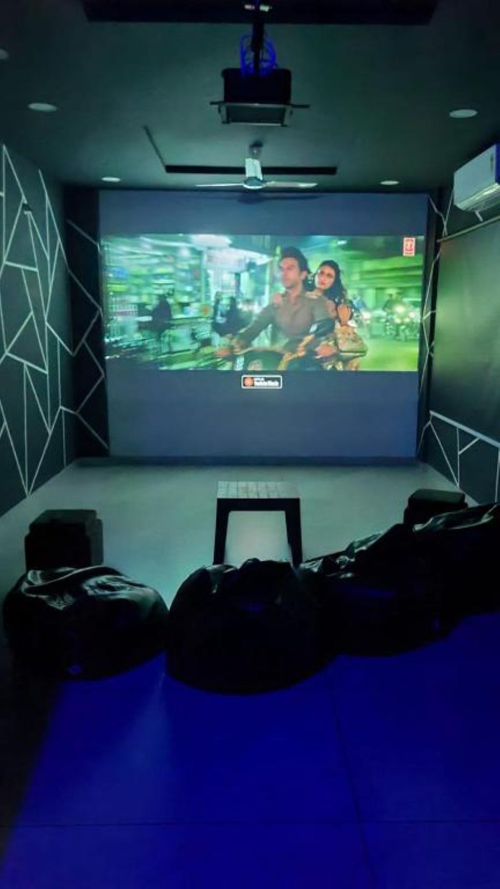 A cinema room with a large screen, seating, and a projector.
