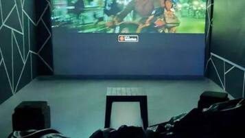 A cinema room with a large screen, seating, and a projector.