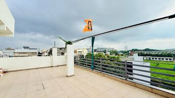 A rooftop terrace with a view of surrounding buildings and a flag.