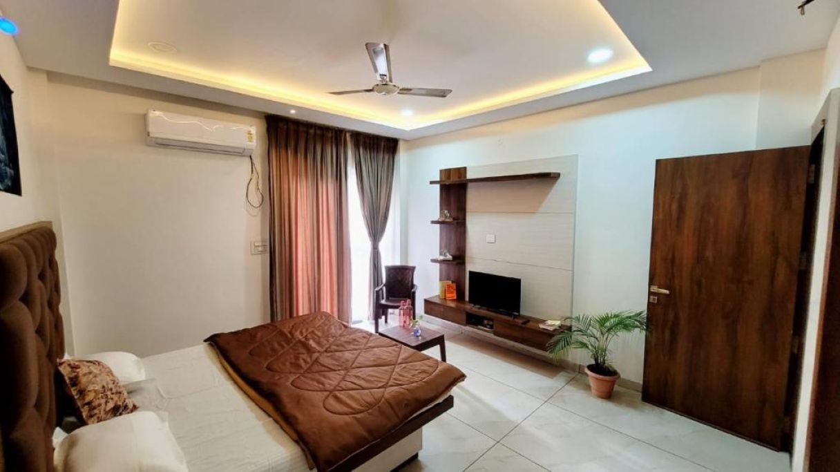 A bedroom with a bed, a TV, a wardrobe, and a ceiling fan.