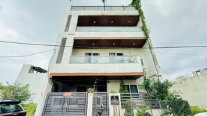 A multi-story residential building with a gated entrance, balconies, and a car parked in front.