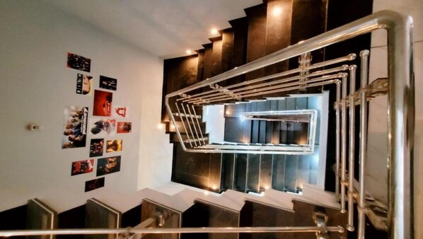 A modern staircase with metal railings and a series of framed pictures on the wall.