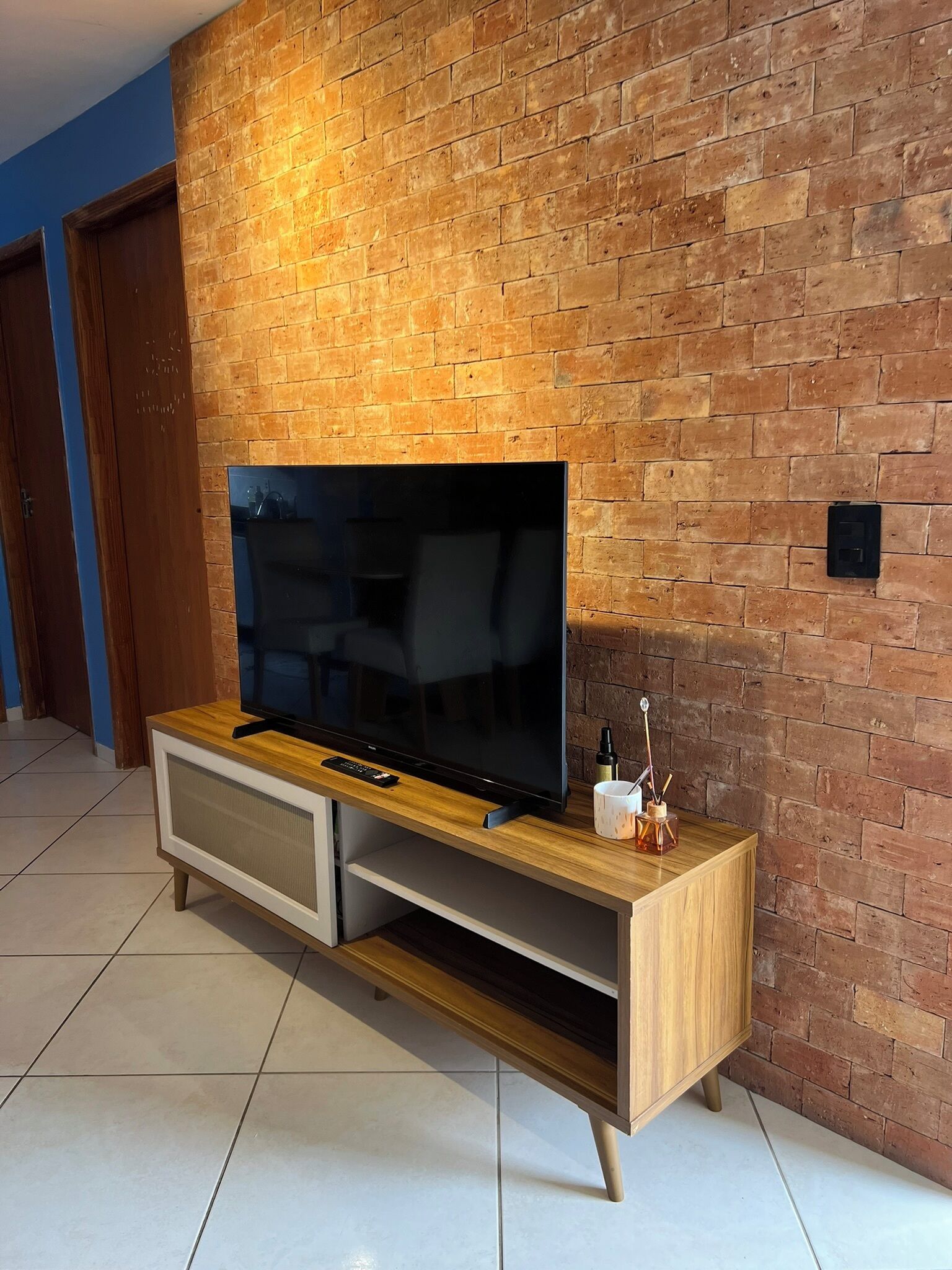 Un televisor de pantalla plana sobre un mueble de madera, frente a una pared de ladrillo.