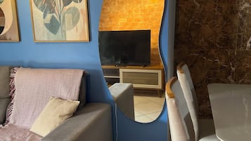 Un salon comprenant un canapé, un téléviseur, une cheminée et un coin repas avec des chaises.