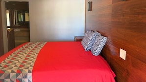 A hotel room with a bed, a wooden headboard, a red bedspread, and a geometric-patterned pillow. - LISA MOTEL (Lake Worth Beach)