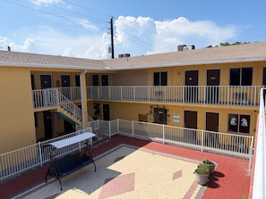 A two-story motel with a central courtyard, outdoor seating, and a fenced balcony area.