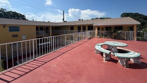 Un edificio con techo rojo, un patio cercado y una zona de estar circular al aire libre.