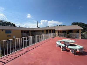 A building with a red roof, a fenced patio area, and a circular outdoor seating area.