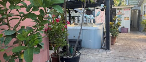 A hot tub area with a pergola, potted plants, and a sign for 'Spa Rules'.